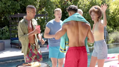 portrait of happy diverse group of friends having barbecue and dancing at pool party in summer