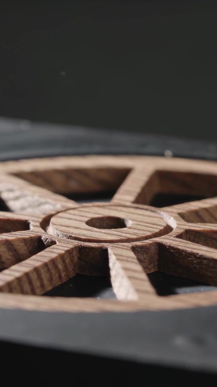 Vertical video: Pulling back, camera revealing carved wooden wheel on studio table, to show grain
