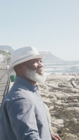 vertical video of senior african american man on promenade by the sea, slow motion