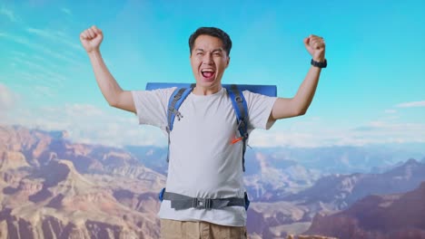 asian male hiker with mountaineering backpack screaming goal celebrating the success while traveling at the top of mountain