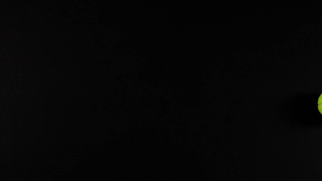 Tennis balls moving against a dark background