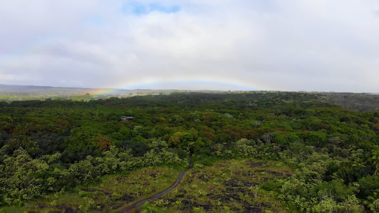 Slow glide over forest and road with rainbow