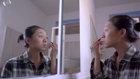 asian woman doing makeup at home