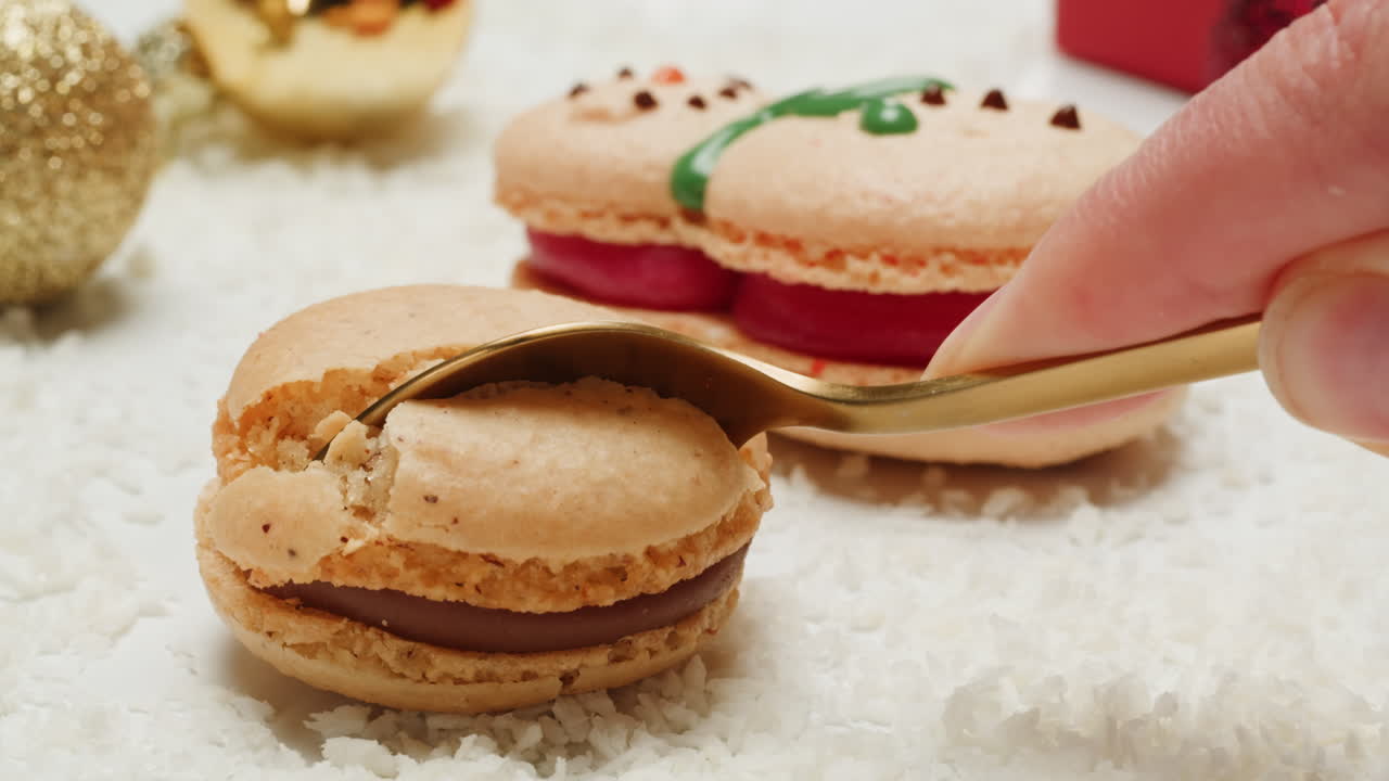 Hand holding a christmas macaron with a gold spoon