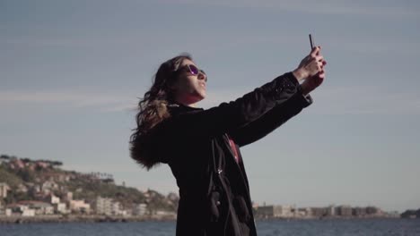 Chica-Toma-Selfie-Y-Fotos-Con-El-Teléfono-Inteligente-En-Cámara-Lenta-Estática-Con-Paisaje-En-El-Fondo