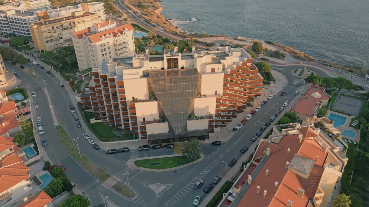 Aerial evening seaside city with road running to ocean waterfront. Coastal town