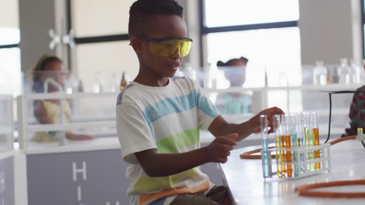 video de un feliz niño afroamericano que usa gafas durante la lección de química