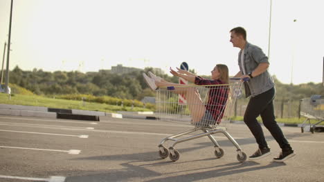 young friends having fun on shopping trolleys. multiethnic young people racing on shopping cart. slow motion