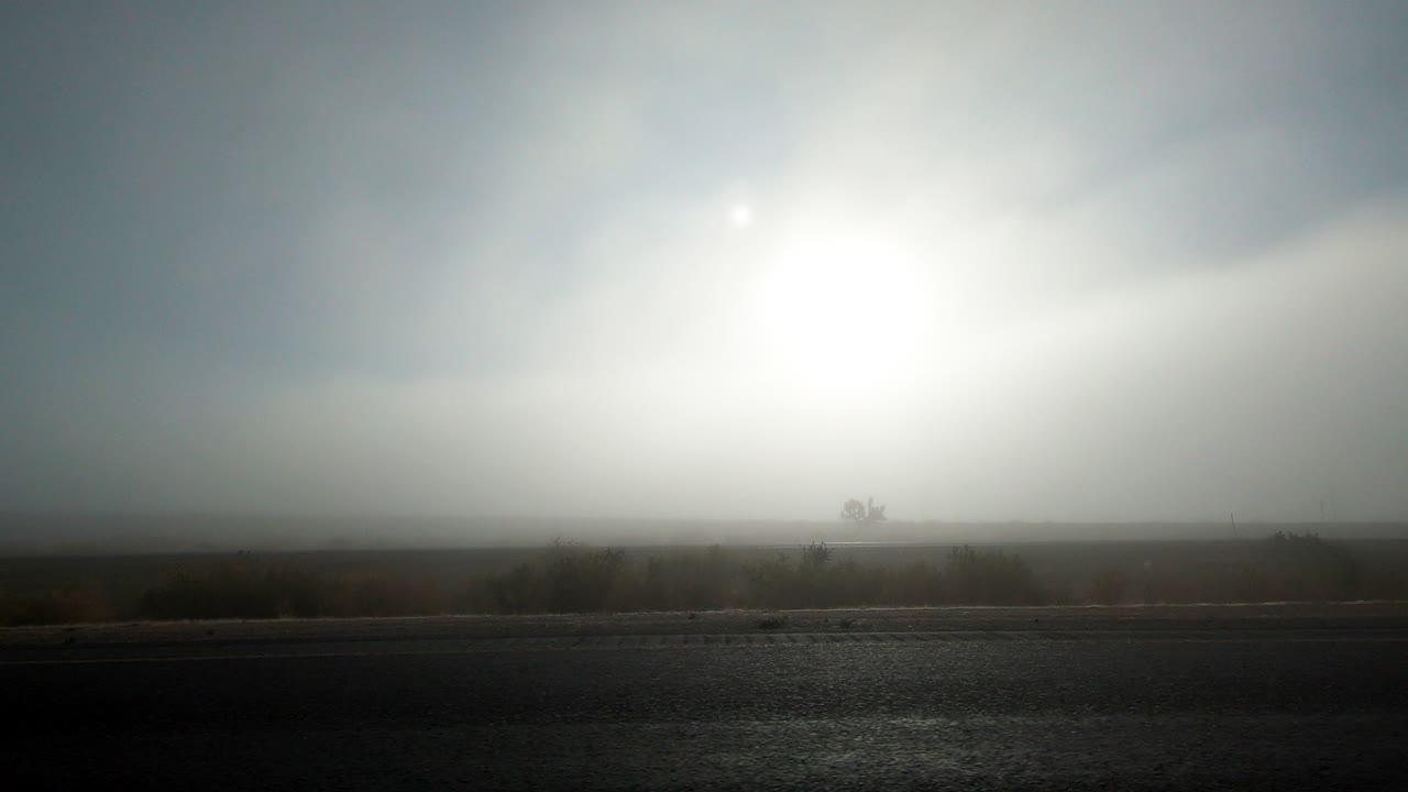 해가 뜨는 동안 캘리포니아의 모하베 사막의 안개가 가득한 풍경을 지나가는 - 넓은 롤링