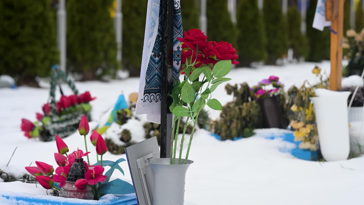 Zoomed-in view of bouquets of flowers resting on the grave of a Ukrainian soldier at Irpin cemetery, located near the site of early battles from the ongoing Ukraine-Russia war, honoring the fallen.