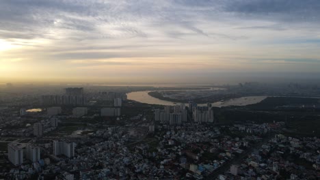 Vista-Aérea-Con-Vistas-Al-Binh-Khanh-Y-Al-Río-Saigón,-Brumoso,-Puesta-De-Sol-En-Ho-Chi-Minh,-Vietnam---Seguimiento,-Disparo-De-Drones