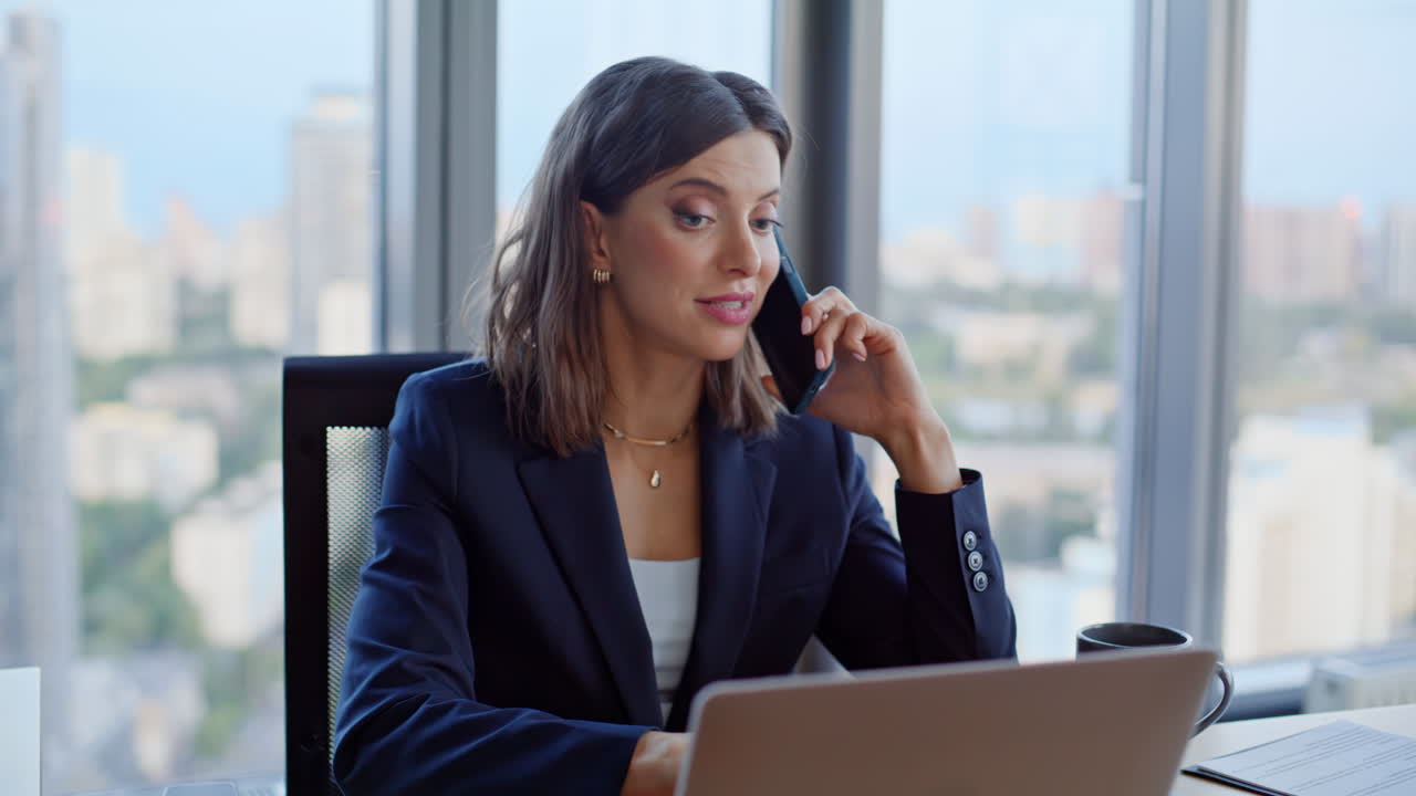 Primo piano di un manager aziendale che negozia al cellulare mentre guarda il portatile in ufficio
