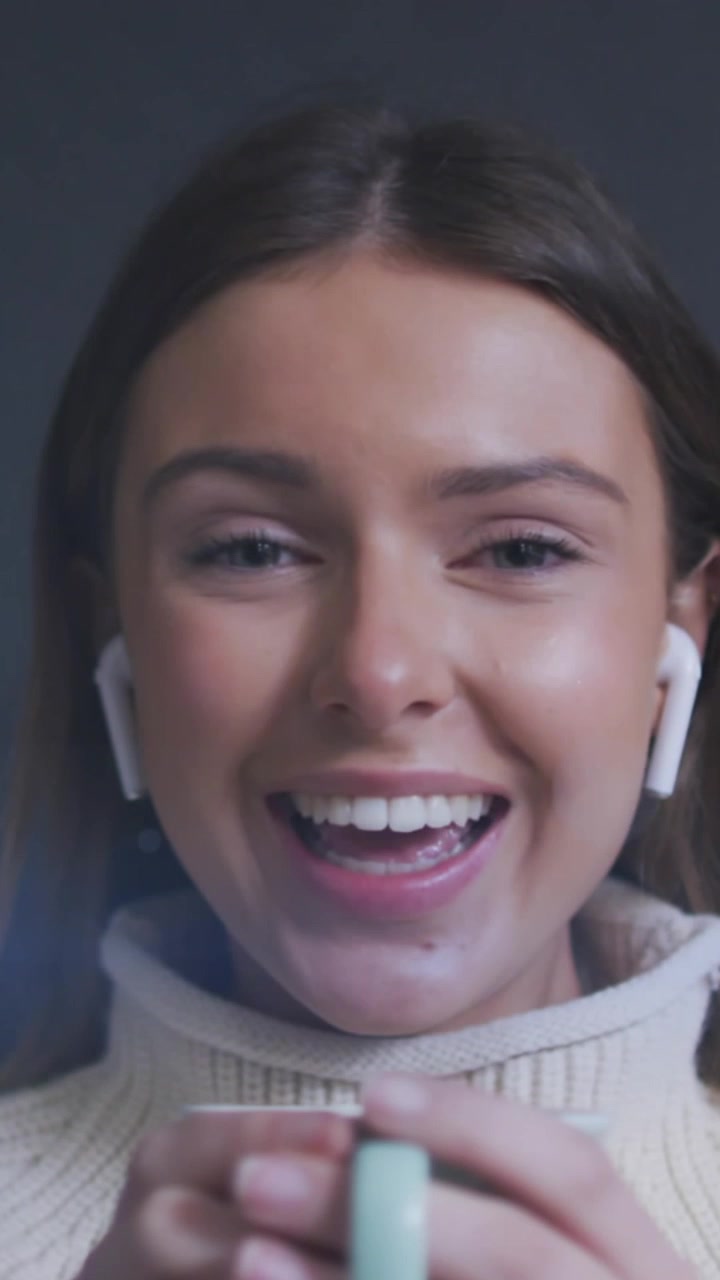 Animation of light spots over smiling caucasian woman drinking coffee and having video call at home