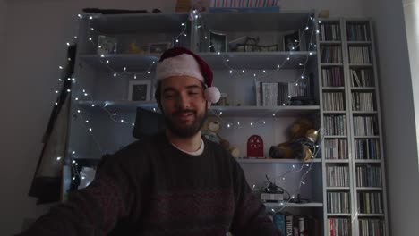 Male-speaking-to-camera-on-videocall,-pressing-the-screen-on-wearing-a-Christmas-hat