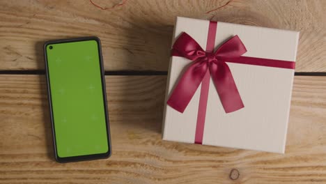 overhead shot of romantic valentines present in gift wrapped box next to green screen mobile phone 1