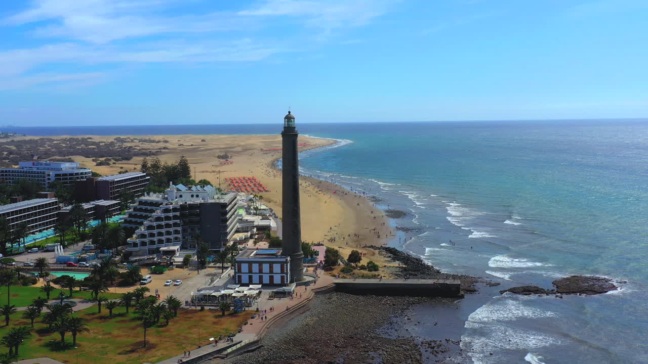 Rotating aerial view of tourist town and lighthouse. Maspalomas, Gran Canaria. Aerial shot of Gran Canaria coast with lighthouse