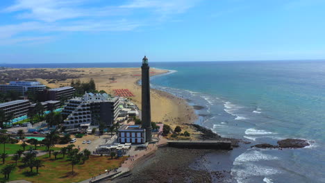 rotating aerial view of tourist town and lighthouse. maspalomas, gran canaria. aerial shot of gran canaria coast with lighthouse