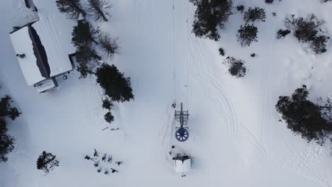 birds eye view drone shot ski lift carrying people on snow mountain