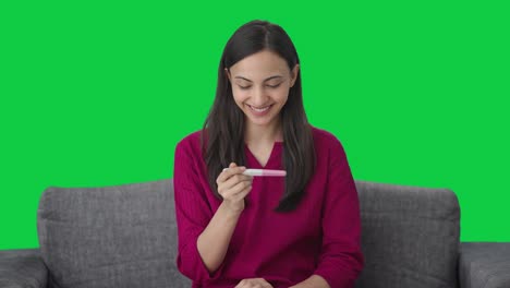mujer india feliz comprobando la prueba de embarazo pantalla verde