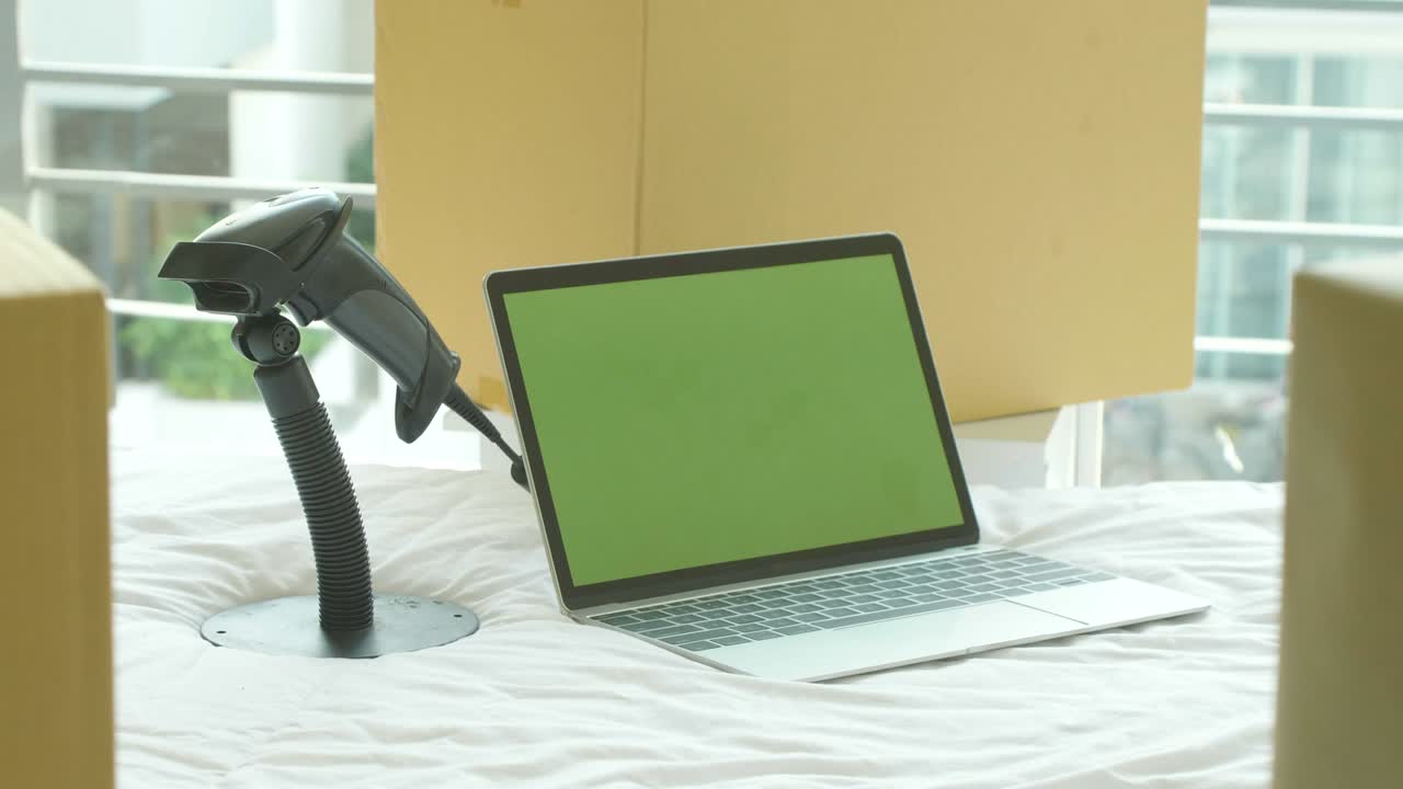 dolly shot: computadora portátil con pantalla verde llave de croma en la cama con cajas de cartón alrededor, concepto de negocio en línea.