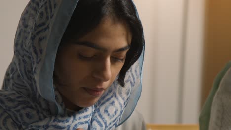 young woman wearing hijab at muslim family table at home eating iftar meal breaking daily fast during ramadan