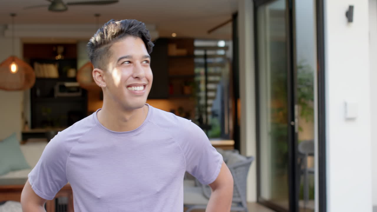 Standing outside modern home, smiling man enjoying outdoor space, copy space