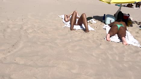 joven en forma tomando el sol en una toalla en un bikini blanco