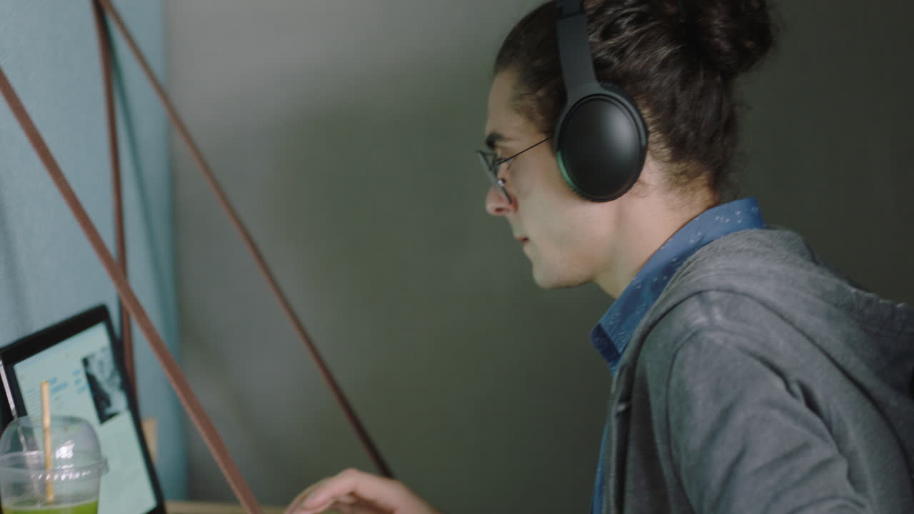 young caucasian man student using digital laptop computer working brainstorming business ideas browsing online study in private office cubicle listening to music wearing headphones
