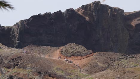 People-wander-on-hiking-trail-by-majestic-cliff-at-Ponta-de-Sao-Lourenco-Madeira,-Portugal