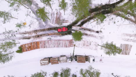 forwarder and grapple loader move and load logs in snowy woodland, top drone