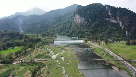 Majestätische-Luftaufnahme-Des-Flusses-In-Vietnam,-Flug-über-Brücke,-Wasseroberfläche-Und-In-Der-Nähe-Der-Natürlichen-Schlucht-Und-Hügel