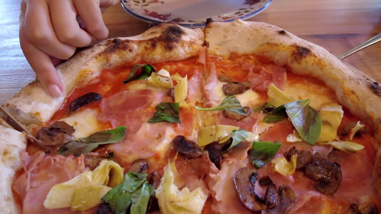 Donna che taglia una pizza su un tavolo in un ristorante
