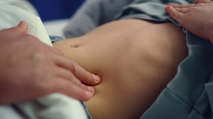Doctor hands checking stomach of little sick girl in hospital ward closeup.