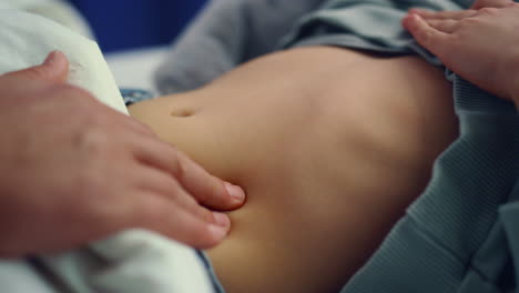 doctor hands checking stomach of little sick girl in hospital ward closeup.