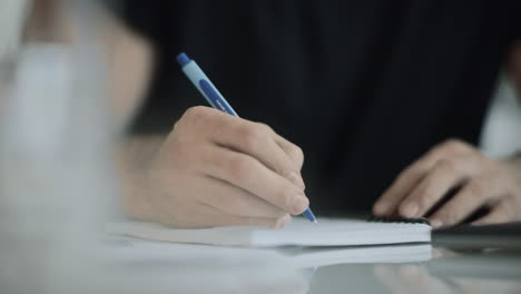 Man-hand-writing-with-pen-at-dairy.-Close-up-of-business-man-hand-write-notes