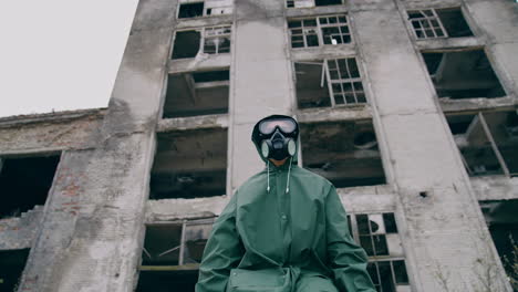 portrait of a man in safety suit in radiation zone. person in gas mask and protective uniform standing alone on ruined building background. apocalypse concept.