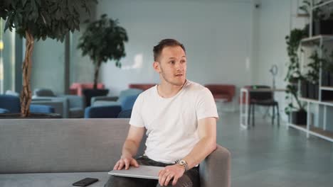 tired man in the business center lobby, sitting with a laptop, concludes his work, feeling upset after a bad, unsuccessful workday