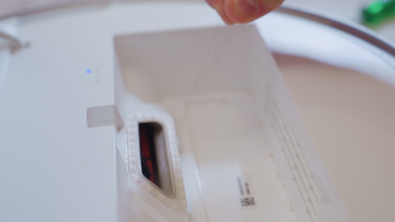 Primer plano del compartimento de un aspirador que muestra un mechón de pelo largo atrapado en el interior durante el proceso de limpieza y mantenimiento, destacando el cuidado y la reparación del electrodoméstico.