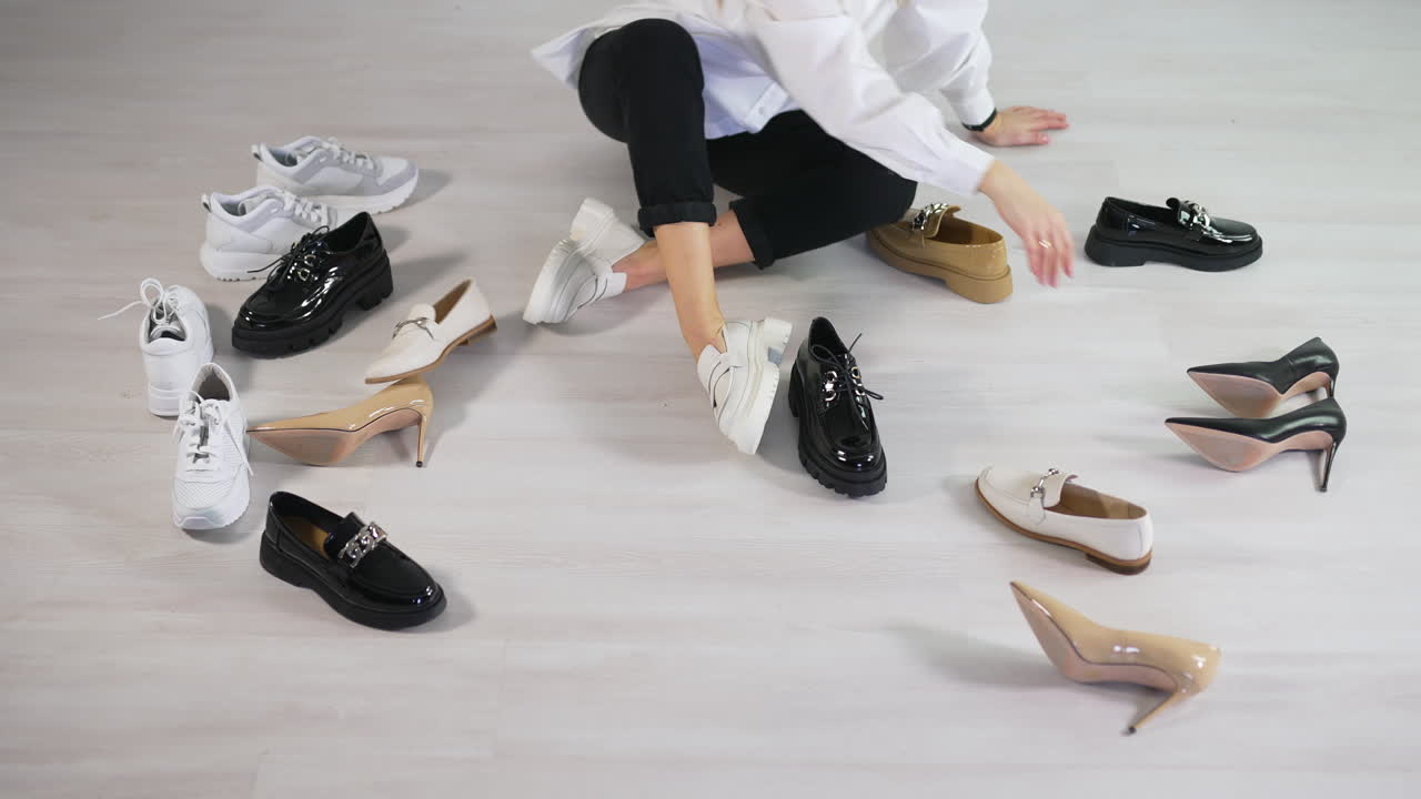 Lady looking over different kinds and styles of footwear. Hard choice decision of a new pair of shoes. Light floor backdrop.