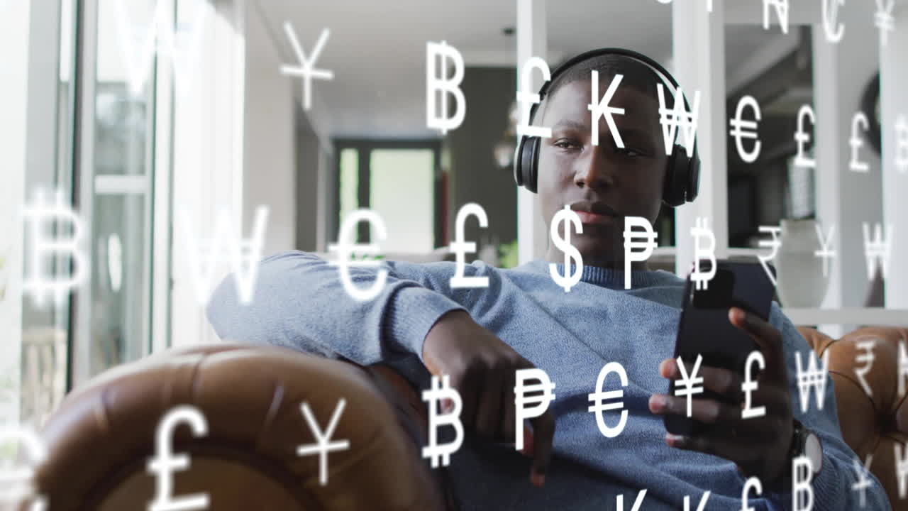 Animation of currency symbols over african american man using smartphone