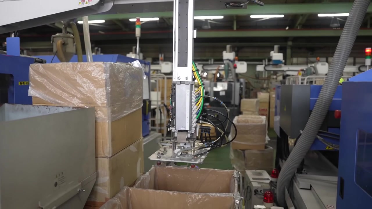 Reparto di stampaggio a iniezione con robot di prelievo e scatole di pezzi stampati