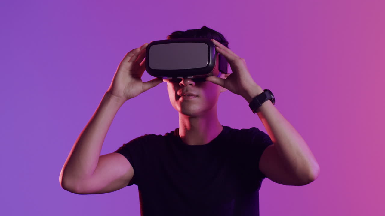 hombre asiático feliz usando auriculares vr en fondo púrpura, cámara lenta