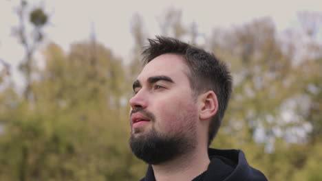 Portrait-Of-A-Bearded-Man-Relaxing-And-Looking-At-Something-While-Standing-At-Park-In-The-Morning