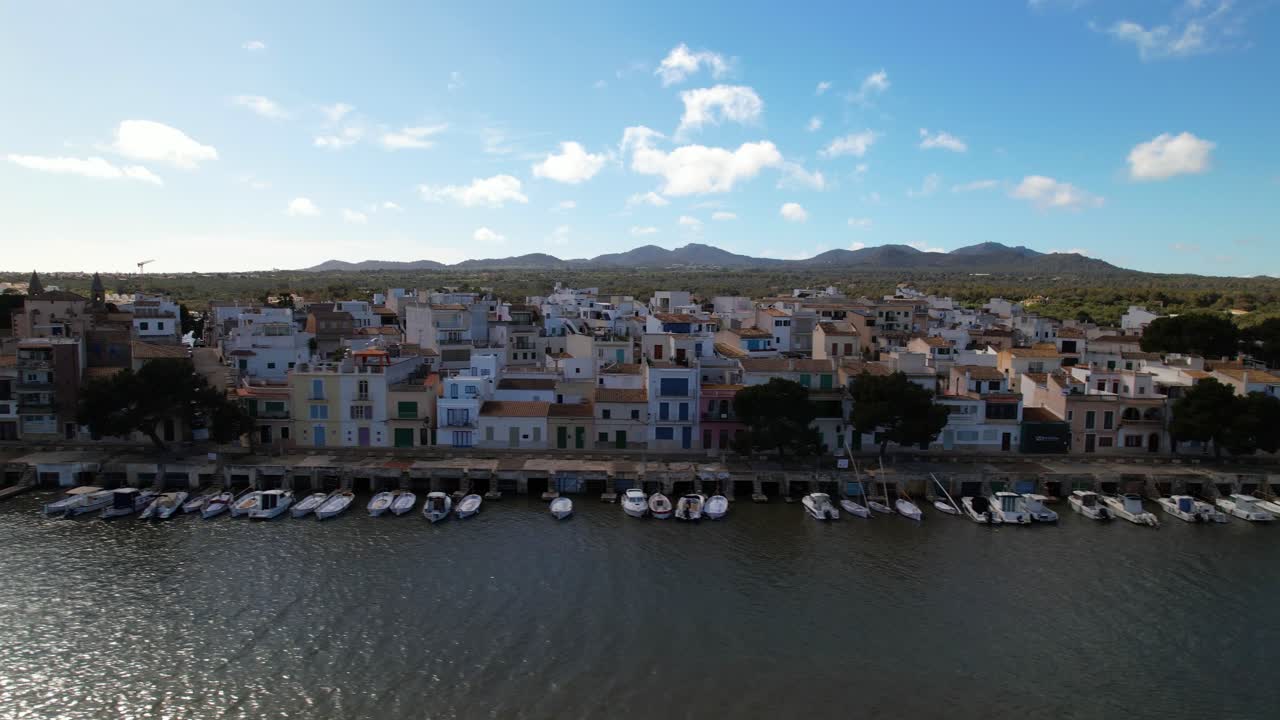 Houses built in typical Mallorcan architectural style directly adjacent to a harbor