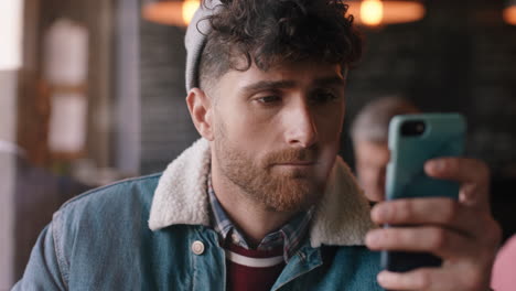 attractive hipster man using smartphone in cafe texting sharing messages on social media enjoying mobile technology relaxing in coffee shop