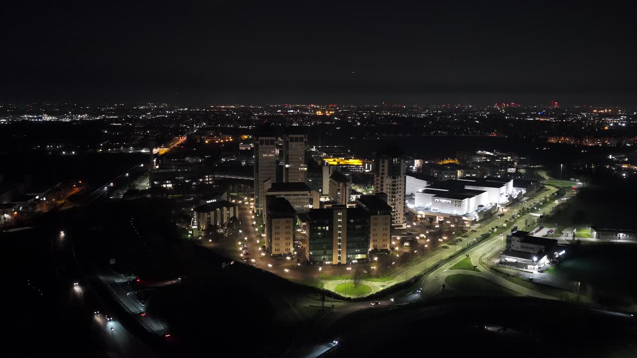 Aerial night view of Vimercate in Lombardy, Italy, featuring illuminated buildings, roads, and surrounding urban landscape