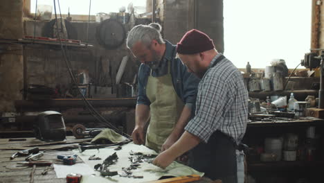 senior blacksmith discussing metal details with colleague