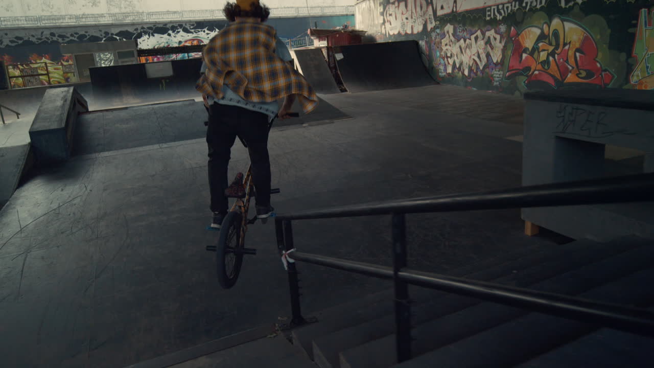 jinete deportivo realizando trucos en bicicleta bmx en el parque de patinaje de la ciudad.