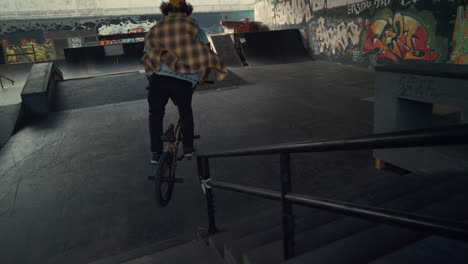 sporty rider performing tricks on bmx bicycle in city skateboarding park.