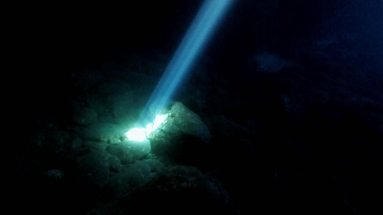 Exploring the dark water of a sea cave enlightened by a natural beam of sun light underwater, Vis island, Adriatic Sea, Croatia
